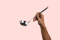 Black male hand holding a silver kitchen ladle isolated o pink background Royalty Free Stock Photo