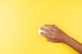 black male hand with white computer wireless mouse on isolated yellow Royalty Free Stock Photo