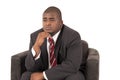 Black male model pondering while sitting is chair wearing a suit Royalty Free Stock Photo