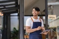 Black male shopkeeper wearing apron with open sign A waitress stands at the entrance to the cafe and food.