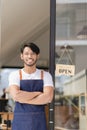 Black male shopkeeper wearing apron with open sign A waitress stands at the entrance to the cafe and food.