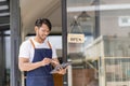 Black male shopkeeper wearing apron with open sign A waitress stands at the entrance to the cafe and food.