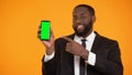 Black male in suit pointing at prekeyed smartphone, place for advertisement