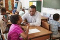 Black male teacher helping elementary school girl in class