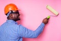 Black man African American holding paint roller in hand paints the wall in pink color .happy african builder painting Royalty Free Stock Photo
