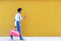 Black man with afro hairstyle carrying a sports bag and smartphone in yellow background. Royalty Free Stock Photo