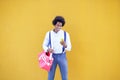 Black man with afro hairstyle carrying a sports bag and smartphone in yellow background. Royalty Free Stock Photo