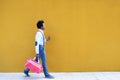 Black man with afro hairstyle carrying a sports bag and smartphone in yellow background. Royalty Free Stock Photo