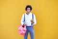 Black man with afro hairstyle carrying a sports bag and smartphone in yellow background. Royalty Free Stock Photo