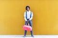 Black man with afro hairstyle carrying a sports bag on yellow background. Royalty Free Stock Photo