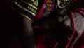 A thoughtful African man in a dashiki and bandana holds beads