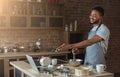 Black man baking pastry and using laptop in kitchen Royalty Free Stock Photo