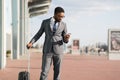 Black Man On Business Trip Using Cellphone Standing Near Airport