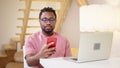 black man checking email and messengers in smartphone when working at home, portrait of african guy