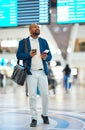 Black man checking flight schedule with phone and ticket walking in airport terminal, holding passport for business trip Royalty Free Stock Photo