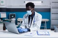 Black man with doctor occupation using laptop on desk