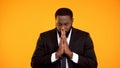 Black man in formal suit praying for successful negotiations important interview Royalty Free Stock Photo