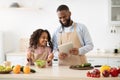 Black man and girl cooking in the kitchen reading recipe Royalty Free Stock Photo
