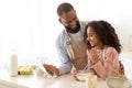 Black man and girl cooking in kitchen using digital tablet Royalty Free Stock Photo