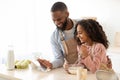Black man and girl cooking in the kitchen using tablet Royalty Free Stock Photo