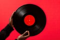 Black man hand holding old vinyl retro record. Vinyl gramophone record on red background. Royalty Free Stock Photo