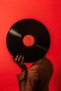 Black man hand holding old vinyl retro record. Vinyl gramophone record on red background. Royalty Free Stock Photo