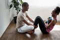 Black man helps his wife pump press, holds her legs