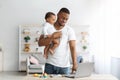 Black Man Holding Little Baby On Hands And Using Laptop At Home Royalty Free Stock Photo