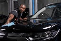 Black man holds the microfiber in hand and polishes the car in auto service Royalty Free Stock Photo