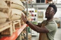 Black Man Inspecting Burlap Coffee Bags on Shelf in Roastery