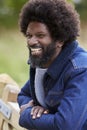 Black man leaning on a wooden fence in the countryside laughing, close up Royalty Free Stock Photo