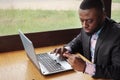 Black man makes payment bank card on laptop buys online, shopping sits in cafe. Royalty Free Stock Photo