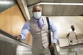 Black man with medical mask climbing subway stairs