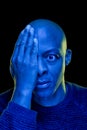 Black man with one eye covered with the hand and amazement expression. Blue light Royalty Free Stock Photo