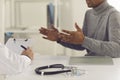 Black man patient sitting and explaining health complaints to man doctor