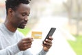 Black man paying with credit card on phone in a park Royalty Free Stock Photo