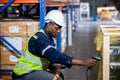 Black man professional worker wearing safety uniform and hard hat worker scanning box inspect product on shelves in warehouse. Royalty Free Stock Photo