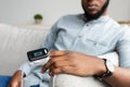 Black Man With Pulse Oximeter Measuring Oxygen Saturation At Home