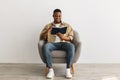Black Man Reading Book Sitting In Armchair On Gray Background Royalty Free Stock Photo
