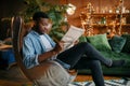 Black man reading newspaper in a comfortable chair