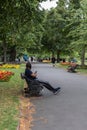 A black man sat on a bench relaxing in the park wearing headphones holding his mobile phone or sell phone Royalty Free Stock Photo