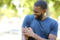 Black man scratching itchy arm in a park