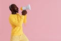 Black man shouting in megaphone on pink background portrait