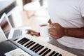 A black man sits in the living room of his apartment and plays a synthesizer. He composes music and drinks coffee. Royalty Free Stock Photo