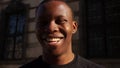 Black man smiling while looking at the camera. Portrait of a young african american man in white t-shirt on city street