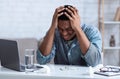 Black man suffering from headache touching head sitting at workplace Royalty Free Stock Photo