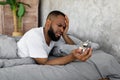 Black man suffering from insomnia looking at clock in bed Royalty Free Stock Photo