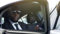 Black man in sunglasses driving car, looking in side-view mirror, bodyguard Royalty Free Stock Photo