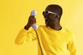 Black man in sunglasses screaming on phone on yellow background Royalty Free Stock Photo