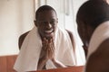 African man looking in mirror cleaning face after shaving Royalty Free Stock Photo